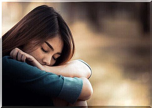 A woman rests her head on her knees