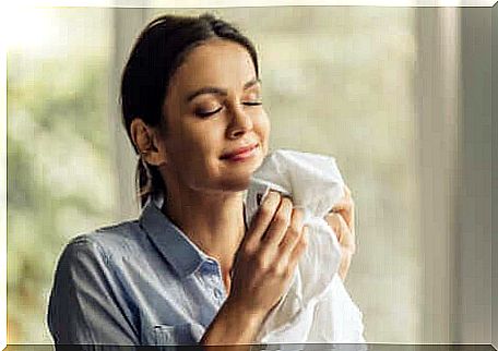 A woman smelling a garment. 